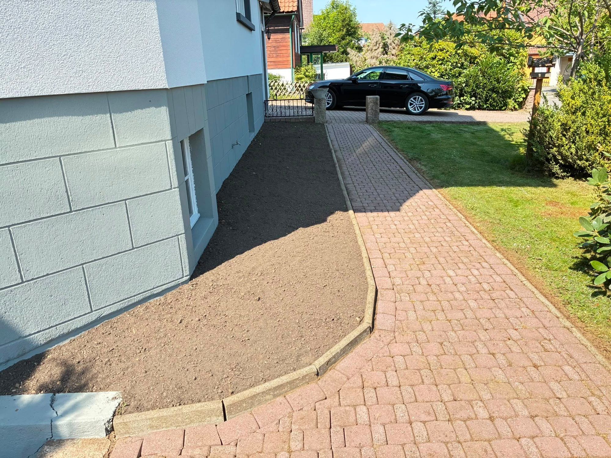 Neu angelegtes Beet am Haus entlang des gepflasterten Wegs