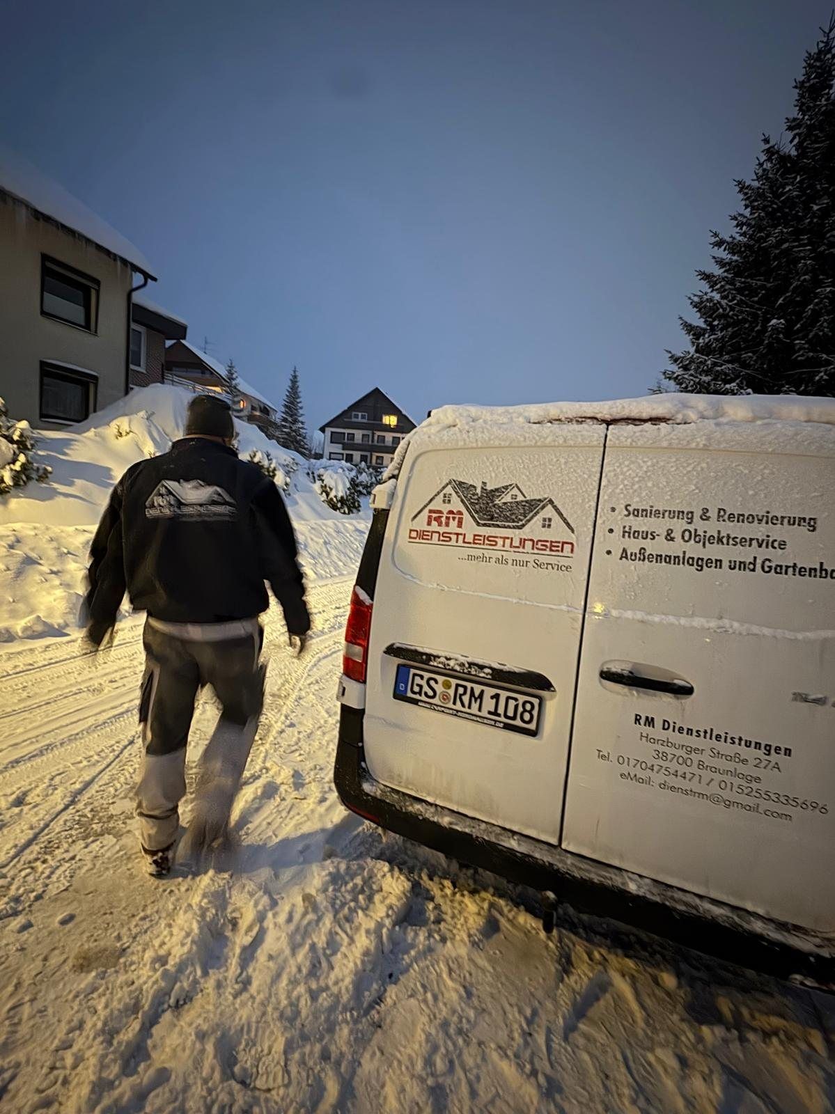 Einsatz im Winter: Mitarbeiter von RM Dienstleistungen am Firmenwagen in verschneiter Straße